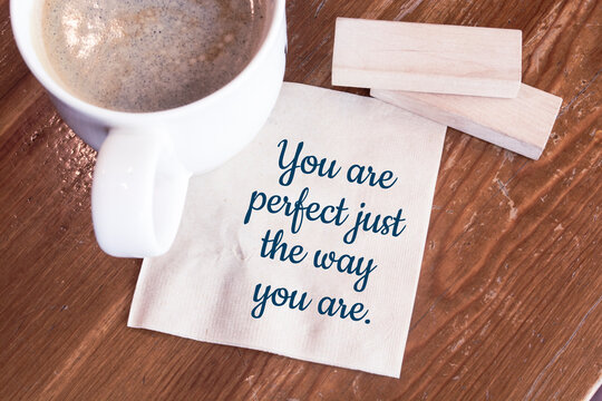 You are perfect just the way you are - handwriting on a napkin with a cup of espresso coffee