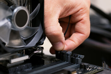 Fototapeta na wymiar Technician man plugging patch cable from aluminum air-cooled heatsink to processor