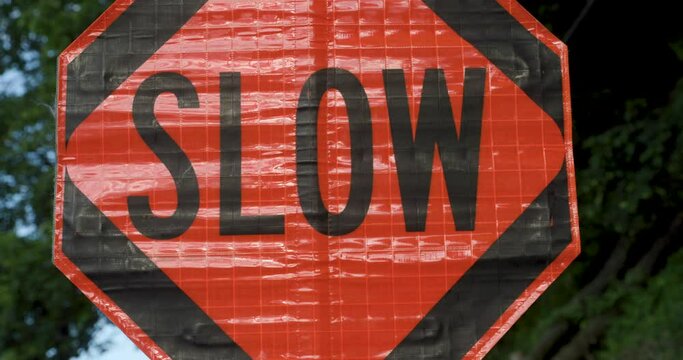 Road Construction Flagger Turning Sign from Stop to Slow While Directing Traffic