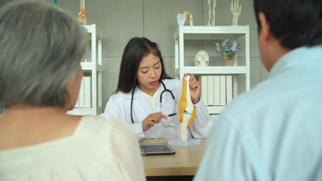 Female orthopedic doctor Explaining the precautions concerning knee and ligaments to elderly female patients and her son listened in the diagnostic room.
