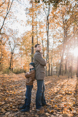 boy with dad in autumn forest with orange leaves