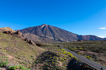 Scenic mountain road leading to volcano Pico del Teide, Mount El Teide National Park, Tenerife, Canary Islands, Spain, Europe. Volcanic dry landscape. Road trip on a sunny summer day. Freedom vibes