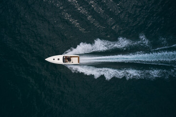 Big white speedboat fast movement on dark water top view. Speedboat with people on the water top view.