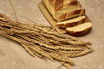 Obraz premium sliced loaf of bread on a cutting board and ears of wheat