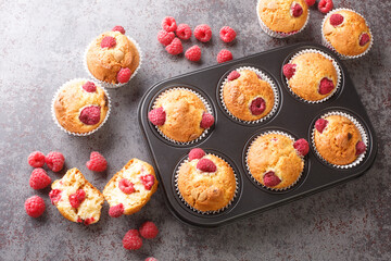 Baked raspberry muffins with white chocolate and fresh berries close-up in a muffin pan on the...
