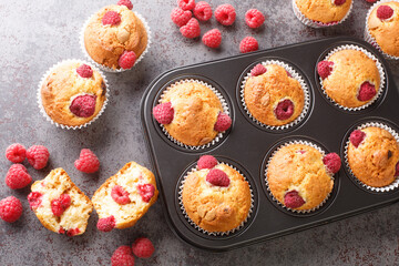 sweet raspberry muffins with white chocolate close-up in a muffin pan on the table. Horizontal top view from above - obrazy, fototapety, plakaty