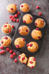 Fresh homemade delicious raspberry muffins closeup on the table. Vertical top view from above