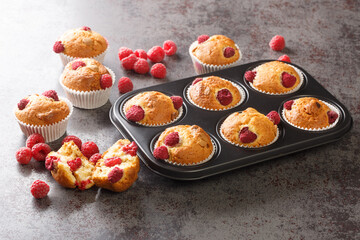Freshly baked muffins with raspberries and white chocolate close-up in a muffin pan on the table. Horizontal