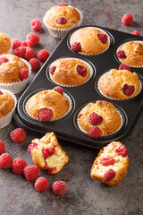 Summer raspberry muffins with white chocolate close-up in a muffin pan on the table. Vertical