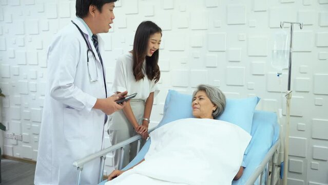 Expert male doctor came in to inquire about the symptoms of an elderly female patient who was lying on the patient's bed. Elderly female patient and her daughter chatting with a male doctor.
