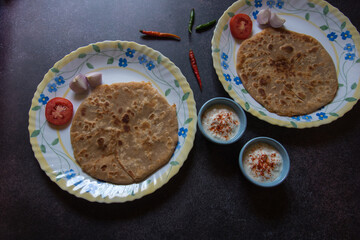 Indian breakfast item aloo paratha or potato stuffed flatbread served. Top view, selective focus.