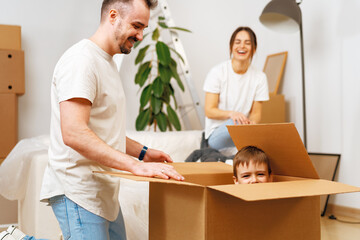 Fototapeta premium Parents and son packing boxes and moving into a new home