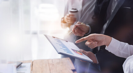 Financial analysts analyze business financial reports on a digital tablet planning investment project during a discussion at a meeting of corporate showing the results of their successful teamwork.