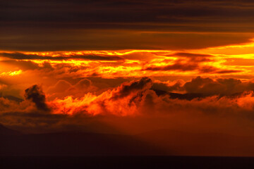 Bright dawn in the sea. Beautiful scarlet and red clouds during a colorful sunrise in Vladivostok.