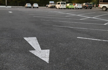 Closeup of arrow sign  on asphalt ground of the parking lot.