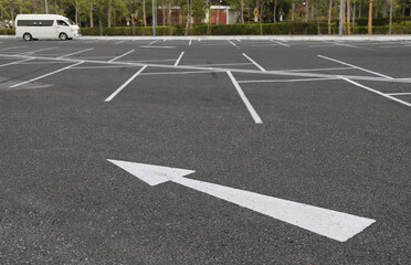 Closeup of arrow sign on asphalt ground of the parking lot.