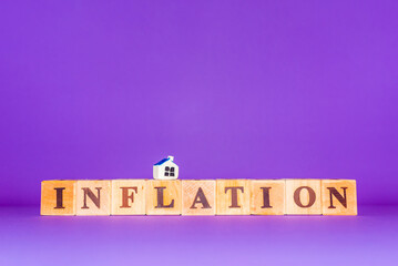 Inflation symbol. Wooden cubes,miniature toy house.Beautiful purple,veri peri background, copy space. Business, inflation concept.