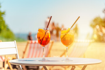 Two glasses of orange spritz aperol drink cocktail on table outdoors sunset with sea and trees view...