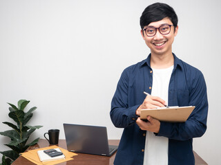 Positive businessman cheerful smile hold document front of workspace in room copy space