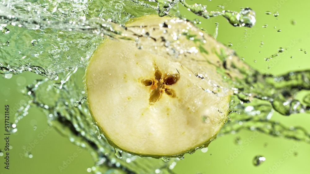 Poster slice of apple with water splashes on green background.