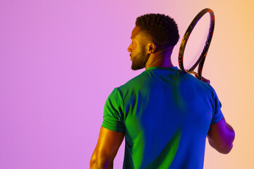 Image of back view of african american male tennis player in violet and yellow neon lighting