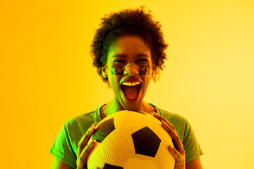 Image of african american female soccer fan with flag of brazil cheering in yellow lighting - obrazy, fototapety, plakaty