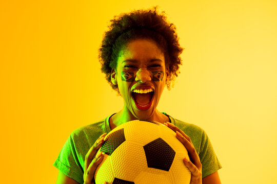 Image of african american female soccer fan with flag of brazil cheering in yellow lighting