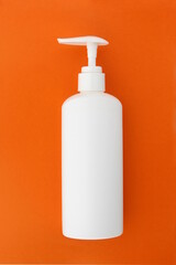 Fototapeta na wymiar On an orange background lies a white bottle with a dispenser.