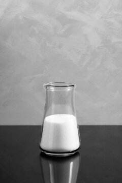 Glass flask with white chemistry powder. Sodium chlorate is a white crystalline powder, used for applications in bleaching pulp to produce high brightness paper
