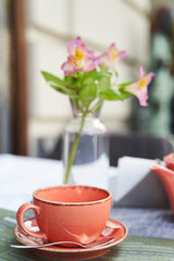 Tbilisi, Georgia - 22.04.2021: Flowers in a vase, a teapot and a cup on the table in a summer outdoor cafe. High quality photo