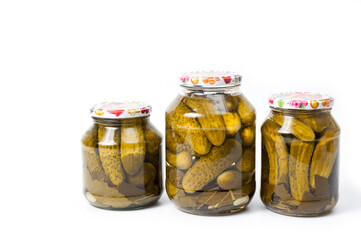 Fresh canned cucumbers in three jars, hermetically sealed with metal lids.