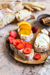 Open sandwiches with artisan bread and cream cheese, nectarines, strawberries and honey, concrete background. Healthy breakfast or snack. Vegetarian food.