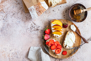 Open sandwiches with artisan bread and cream cheese, nectarines, strawberries and honey, concrete background. Healthy breakfast or snack. Vegetarian food.