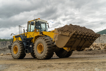 The loader works in an open pit. The bucket contains ore.