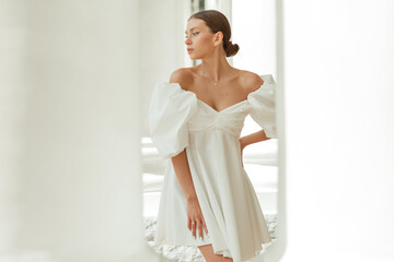 A young beautiful woman in a white dress near the columns