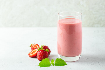 Refreshing mint strawberry smoothie, yogurt milkshake in glass with mint leaves.