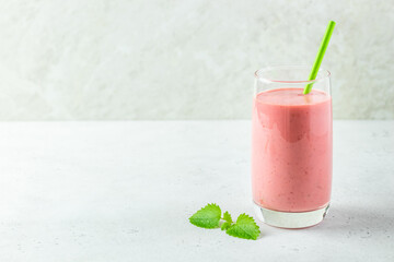 Healthy protein strawberry smoothie, yogurt milkshake in glass with mint leaves.