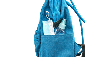 Close up side pocket of blue student backpack with face mask and a small bottle of alcohol, side...