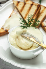 cream cheese and butter for breakfast. melted cheese on light background. vertical image. place for text