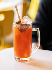 Glass beer mug of tomato gose decorated black salt in a bar interior. Man in black clothes on the background