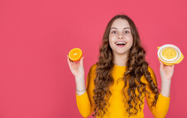 happy teen girl hold orange and juicer on pink background with copy space