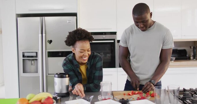 Video of happy african american couple preparing meal together in kitchen