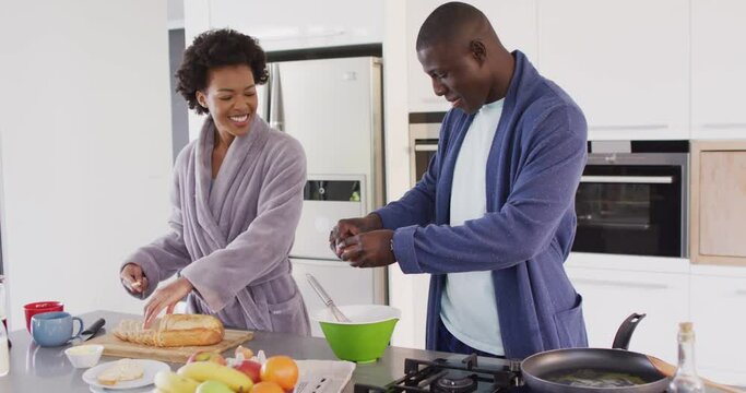 Video of happy african american couple preparing breakfast together in kitchen