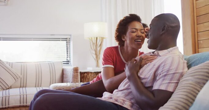 Video of happy african american couple sitting on sofa and talking
