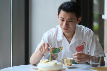 Obraz na płótnie Canvas Asian young man light the candle on birthday cake