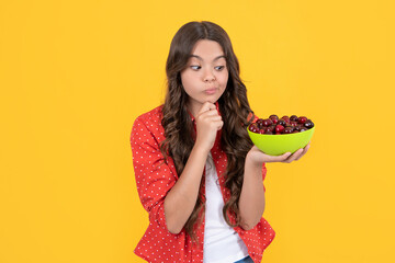 thoughtful teen girl hold cherry bowl on yellow background