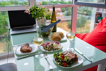 Romantic dinner table setting, wine glasses and fresh salad in bowl, home date