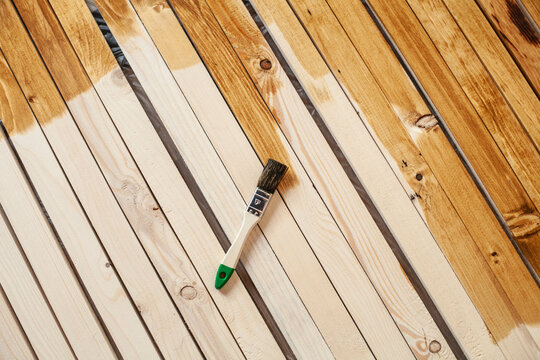 Repair concept. the brush lies on wooden slats. Half of the them is covered and the other is not.