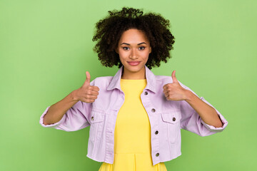 Portrait of good looking female showing thumbs-up rate good quality produce isolated on green color...