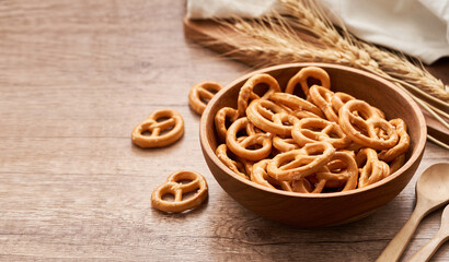 mini salted pretzel in a wooden bowl with a spoon and fork on wood table background. copy space                                  - obrazy, fototapety, plakaty